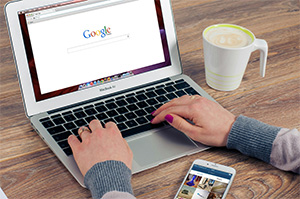 Hands on a laptop keyboard with Google open on the browser