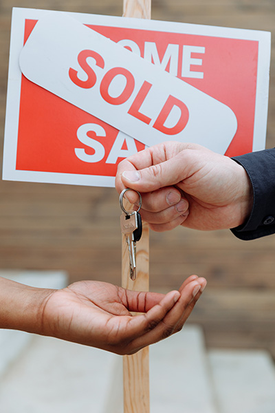 Homes for sale in Tinton Falls SOLD sign in back of hands passing a set of keys